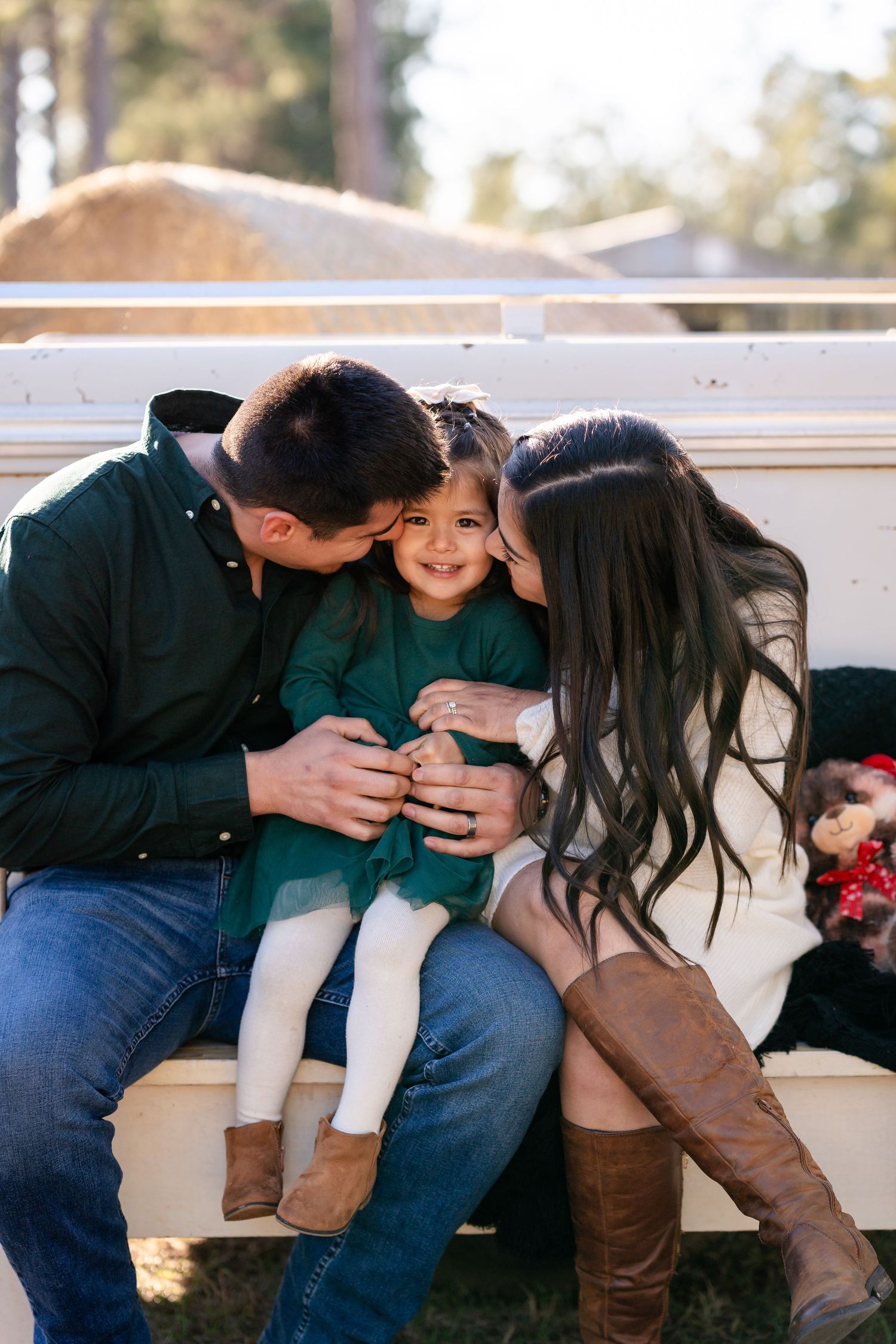An intimate family portrait session on a white bench showcases natural, candid moments.
