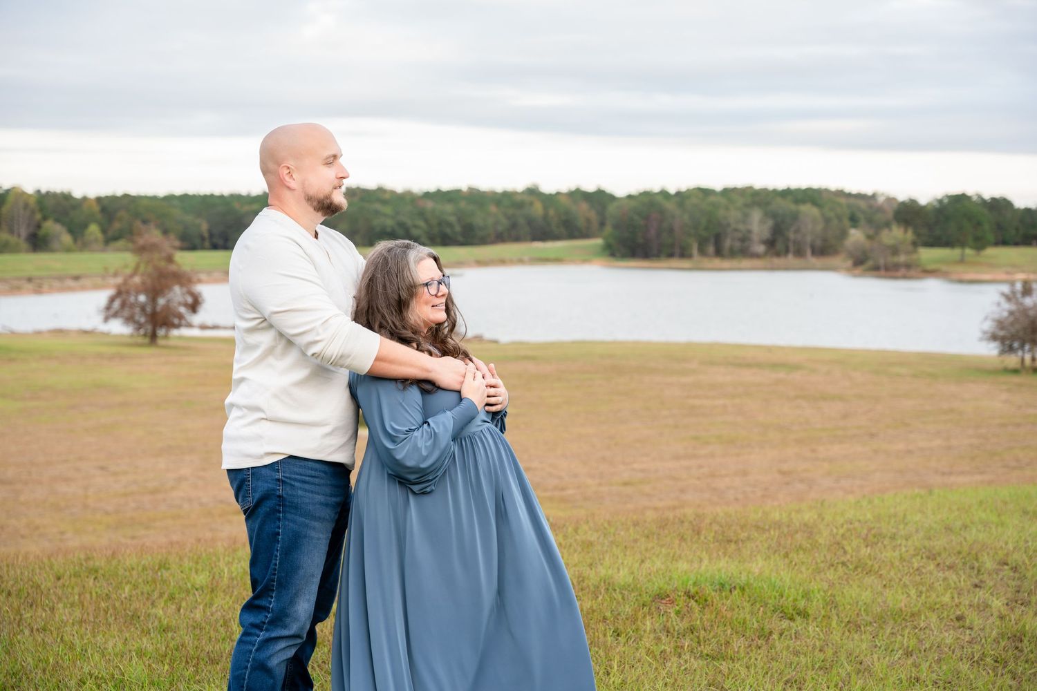 Candid outdoor portraits of couple in white and blue outfits against natural lake backdrop.