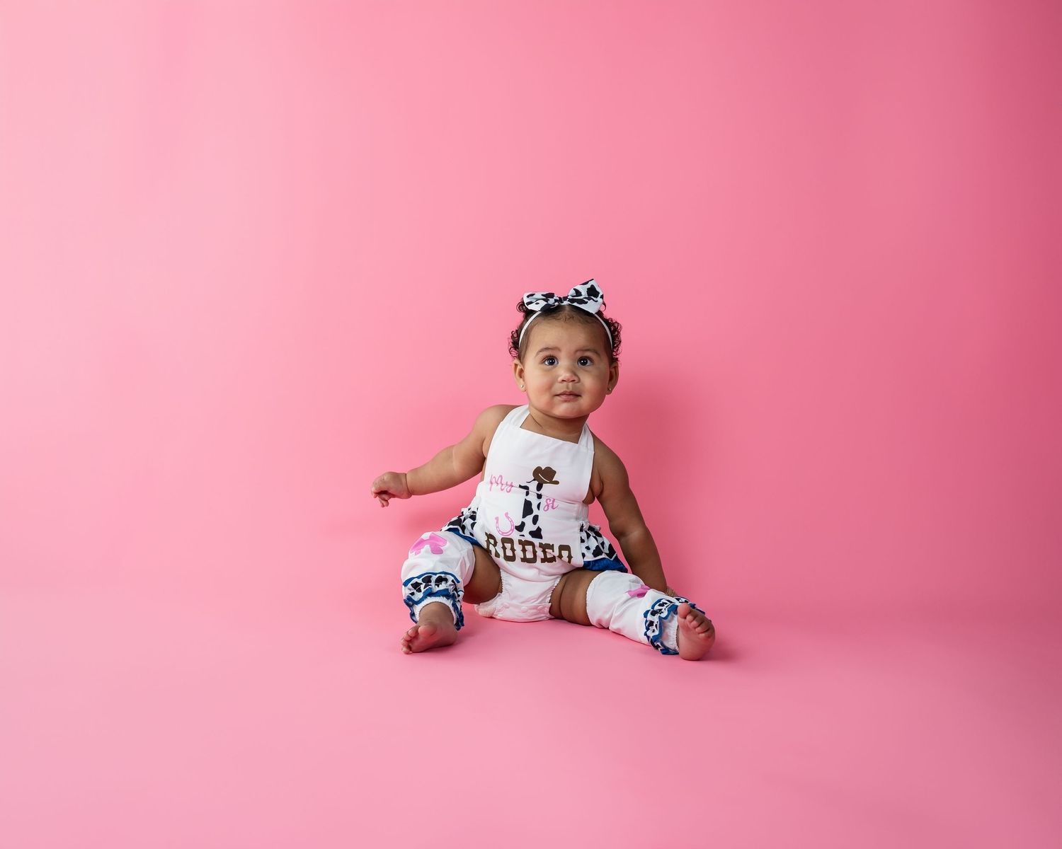 Baby milestone photography session against pink backdrop showing developmental stages.
