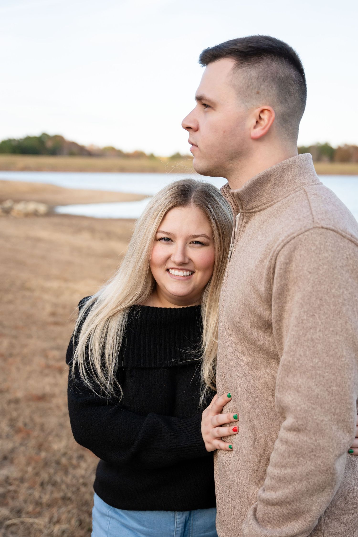 A couple shares intimate moments by a lake during a photo session.