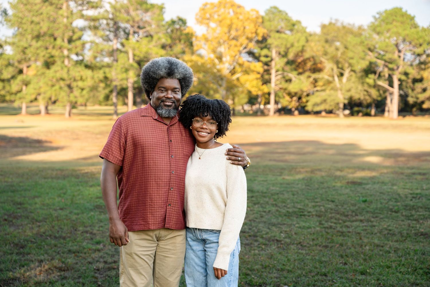 Couple sharing a joyful moment together in a grassy field during autumn.