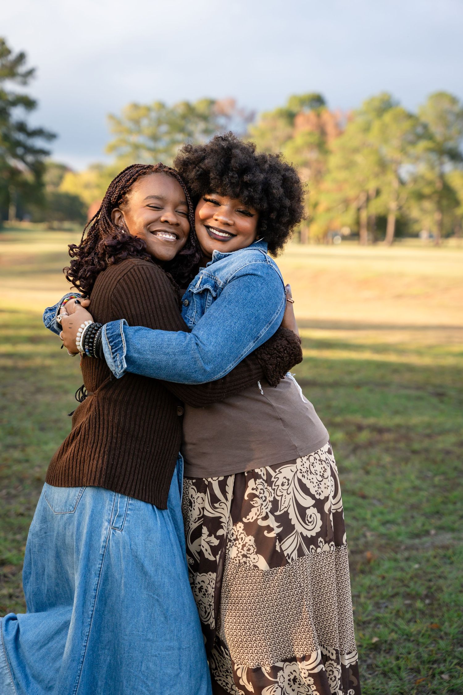 Two people sharing a warm embrace while laughing together in an autumn field setting.