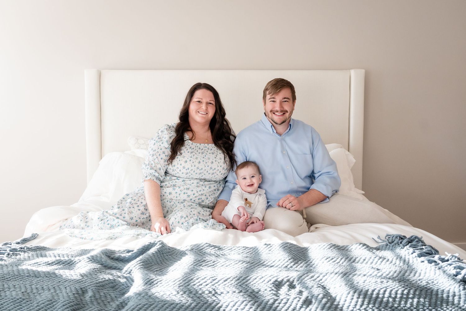 Family lounging together on white bedding during an intimate lifestyle photoshoot.