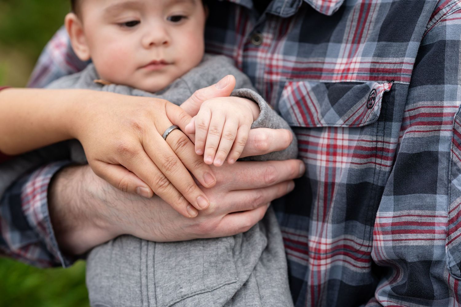 Close-up photos showing gentle hand-holding moments in a plaid shirt.
