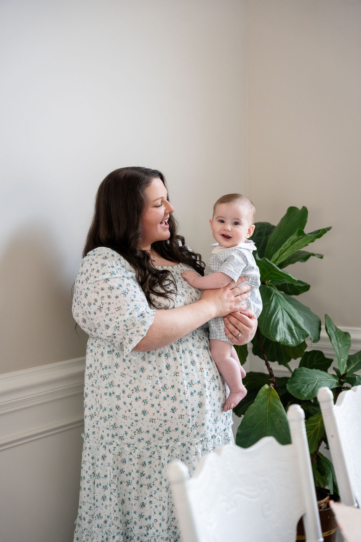 A family moment near a houseplant as a baby is held up with joy and laughter.