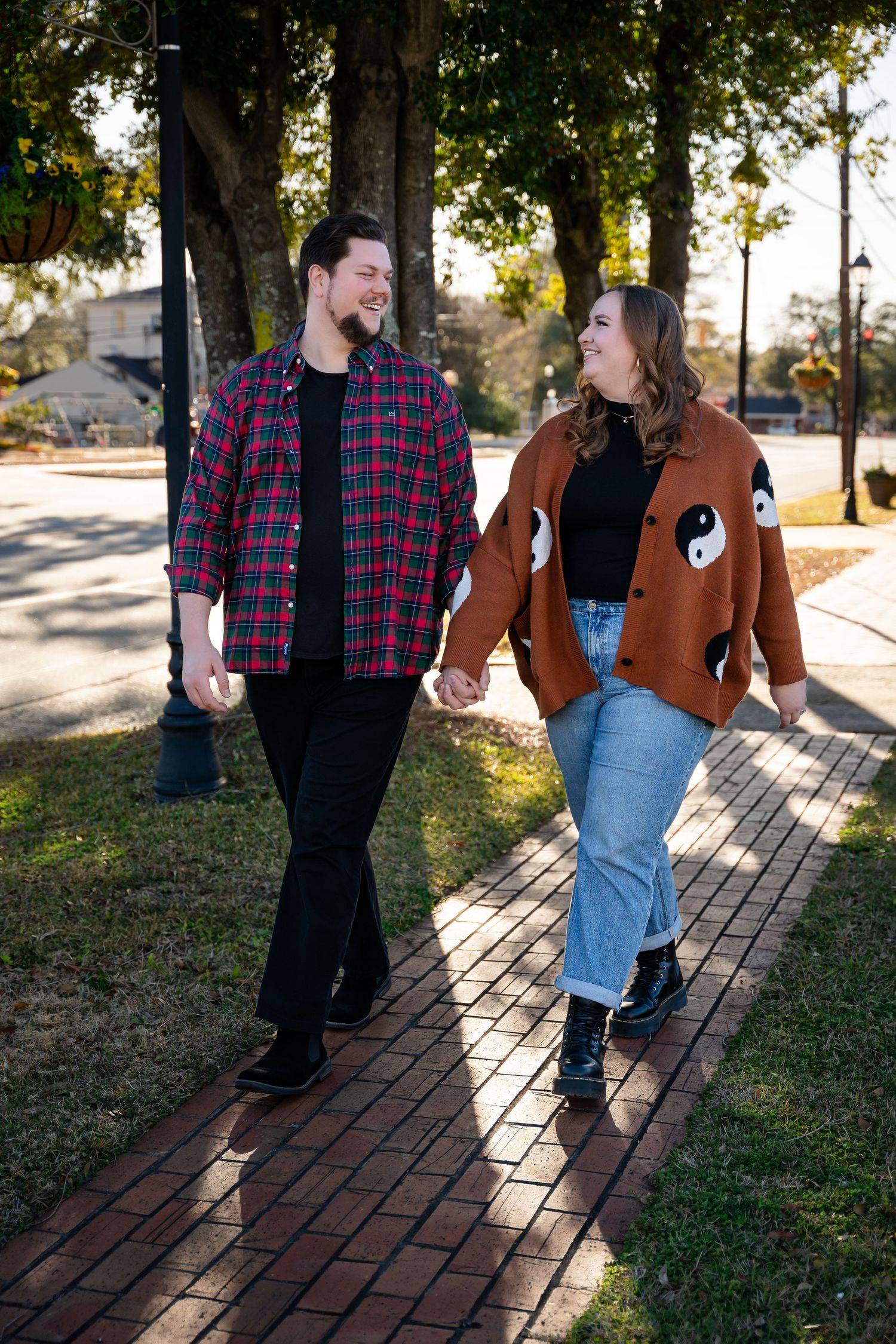 Couple walking on a brick path at sunset wearing plaid and denim.