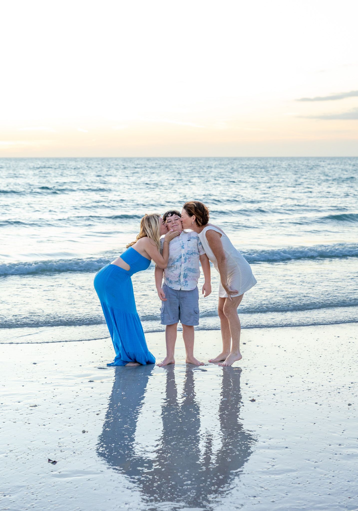 People enjoying a playful moment at the beach during golden hour with ocean waves and reflective wet sand.