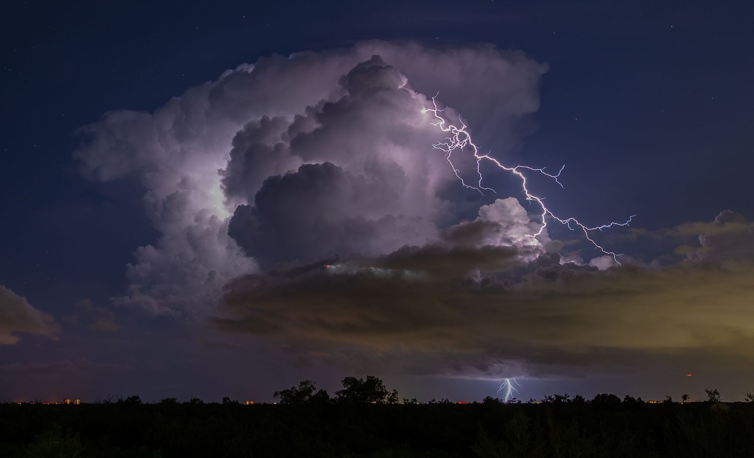 A dramatic lightning storm illuminates the dark night sky with multiple bright bolts striking across the horizon.