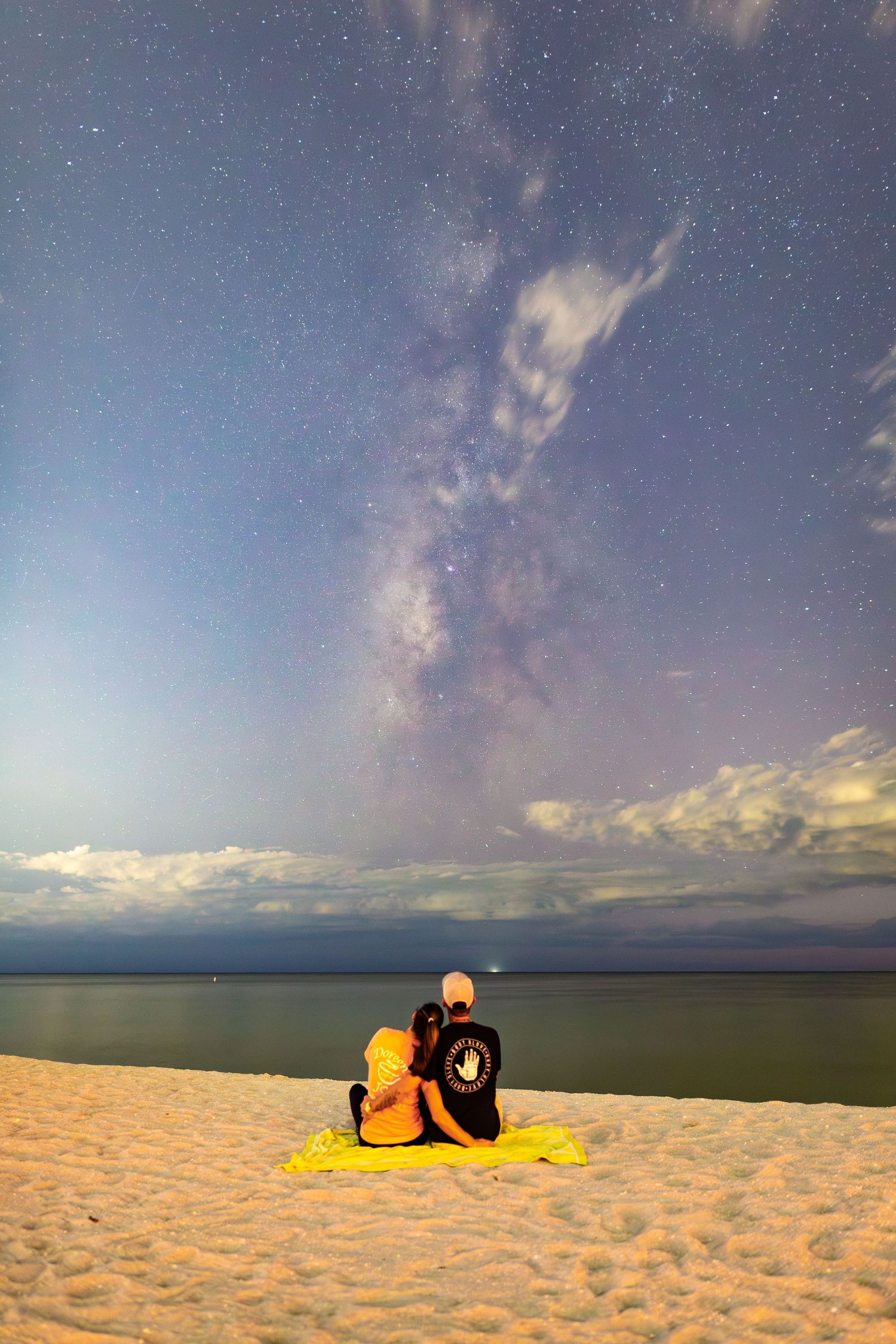 A sequence of starlit beach scenes shows a figure lying on sand under a colorful twilight sky with clouds and ocean horizon.