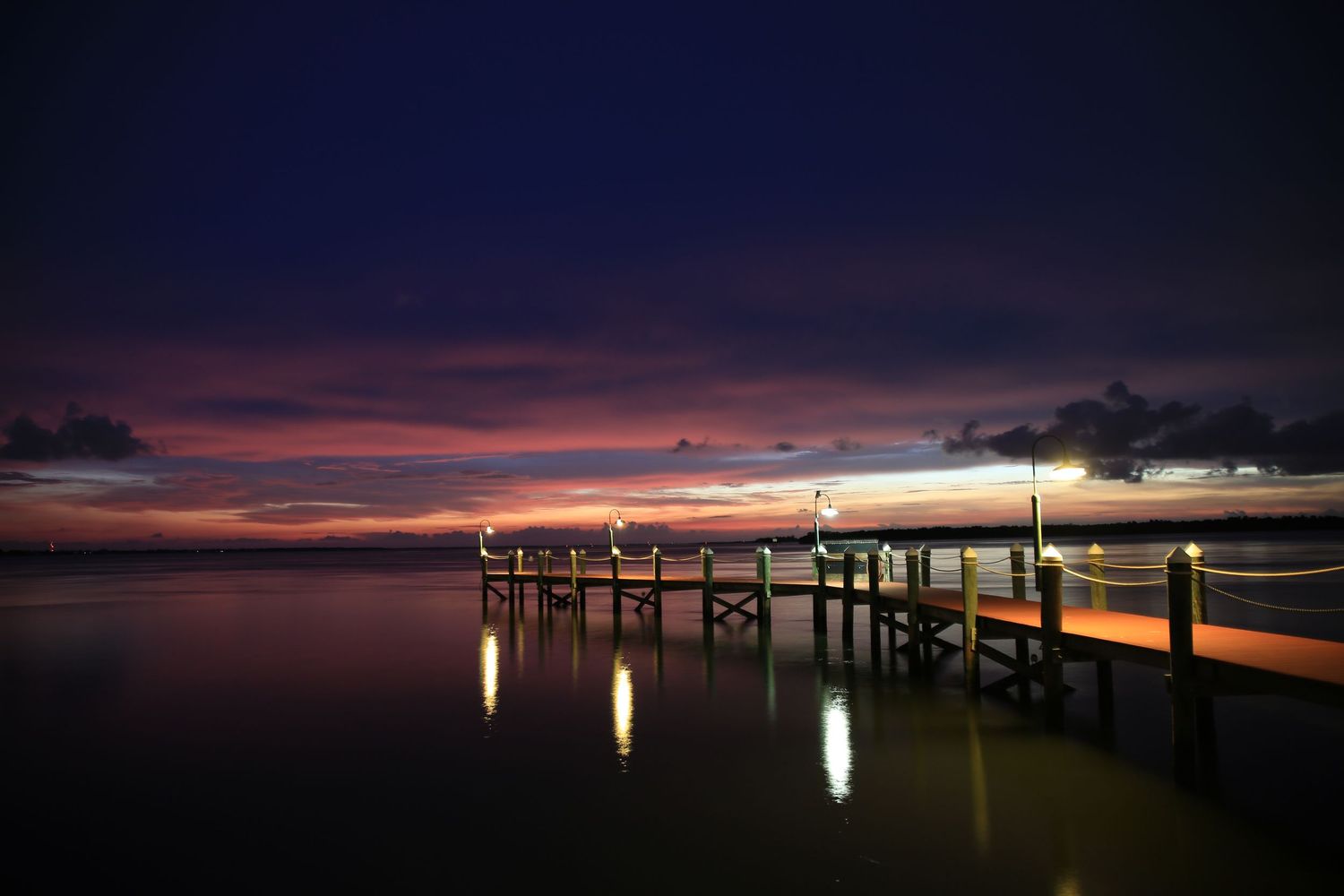 A series of sunset photos showing a wooden pier silhouetted against colorful evening skies with reflections on calm water.