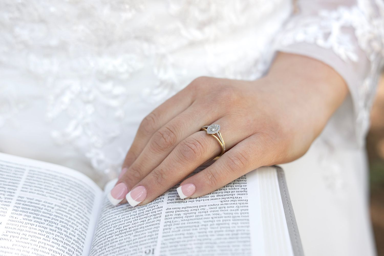 bride's hand on bible wearing a wedding ring