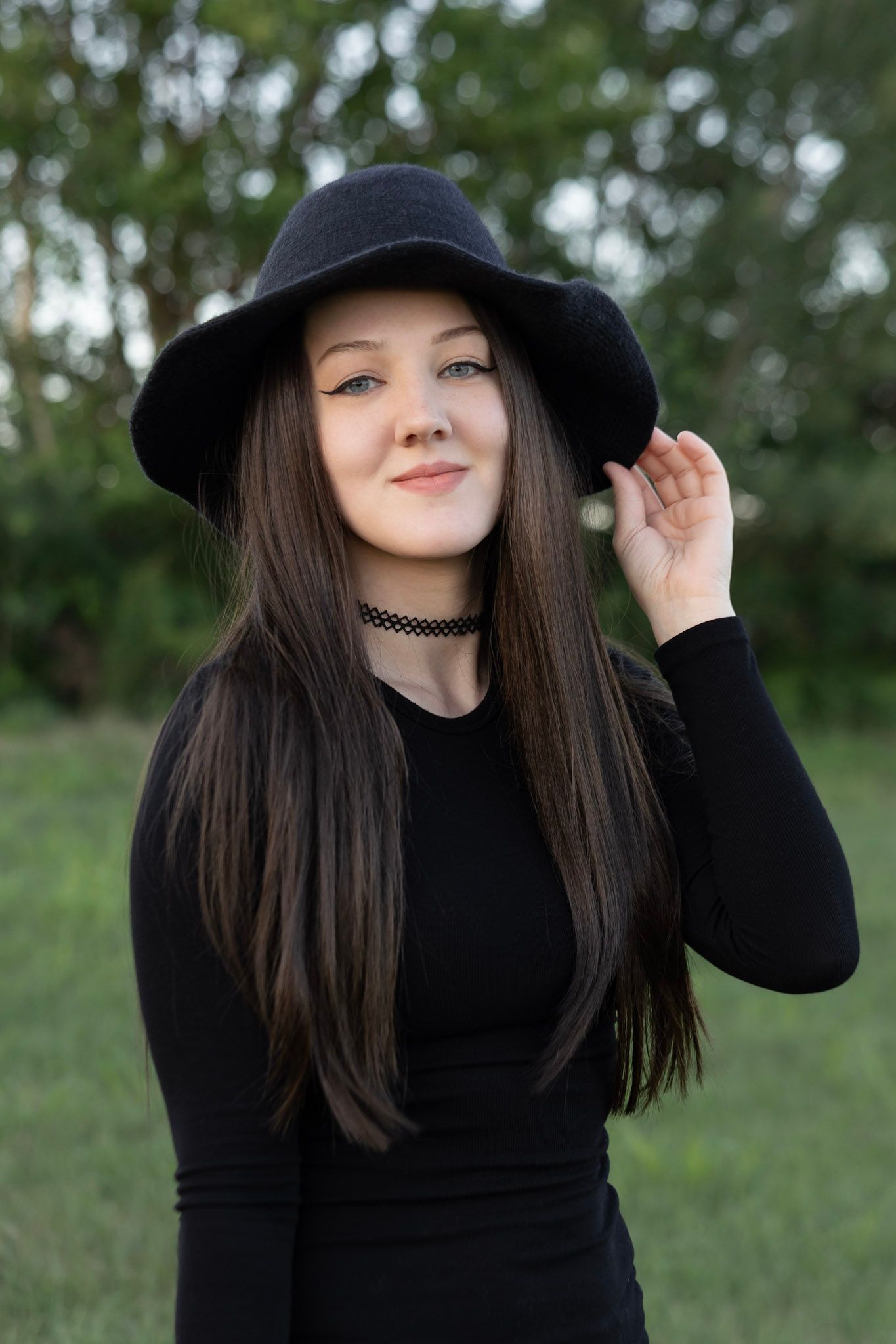 woman wearing black clothing in a witch hat in a greenery outdoor scenery