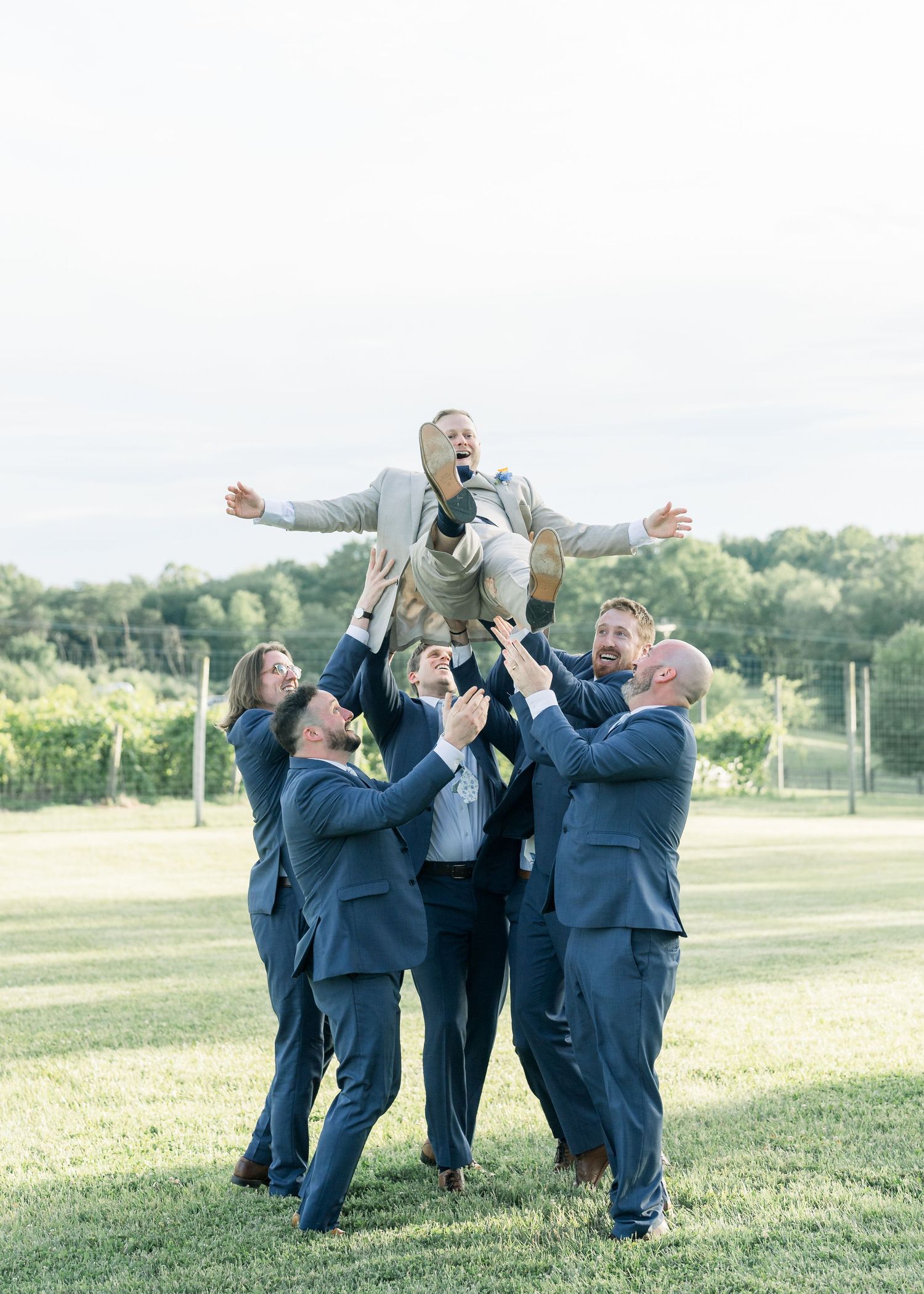 Groomsmen surprising the groom with a toss in the air - The Winery at Bull Run