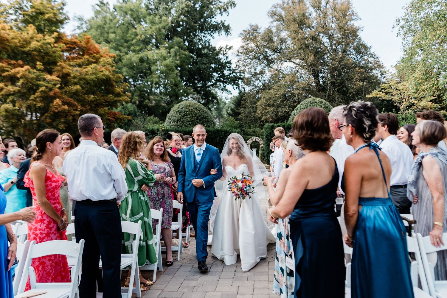 Father of the bride and bride walking down the aisle together, during wedding ceremony at Airlie, Warrenton, Virginia.