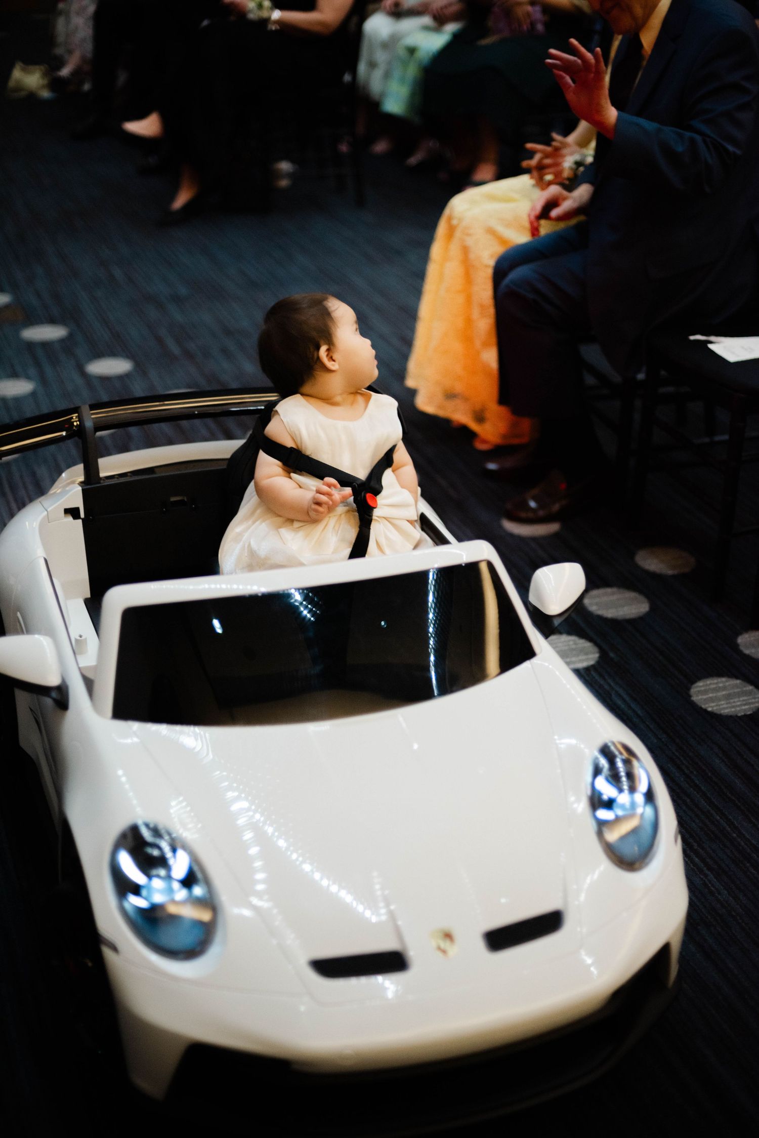 A coming down the aisle in a remote controlled Porsche toy car.