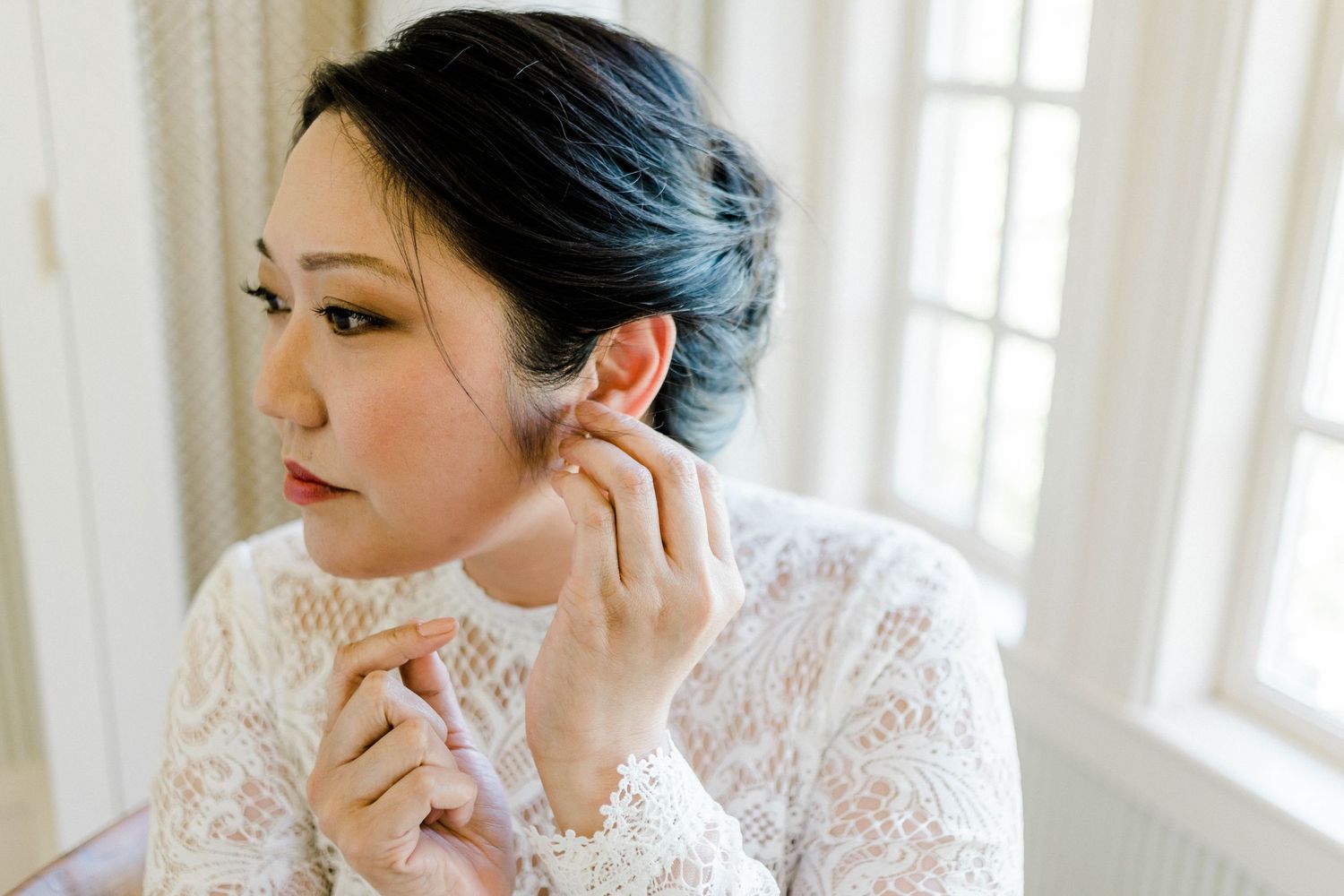 Bride putting earrings on in Bridal suite at Great Marsh Estate