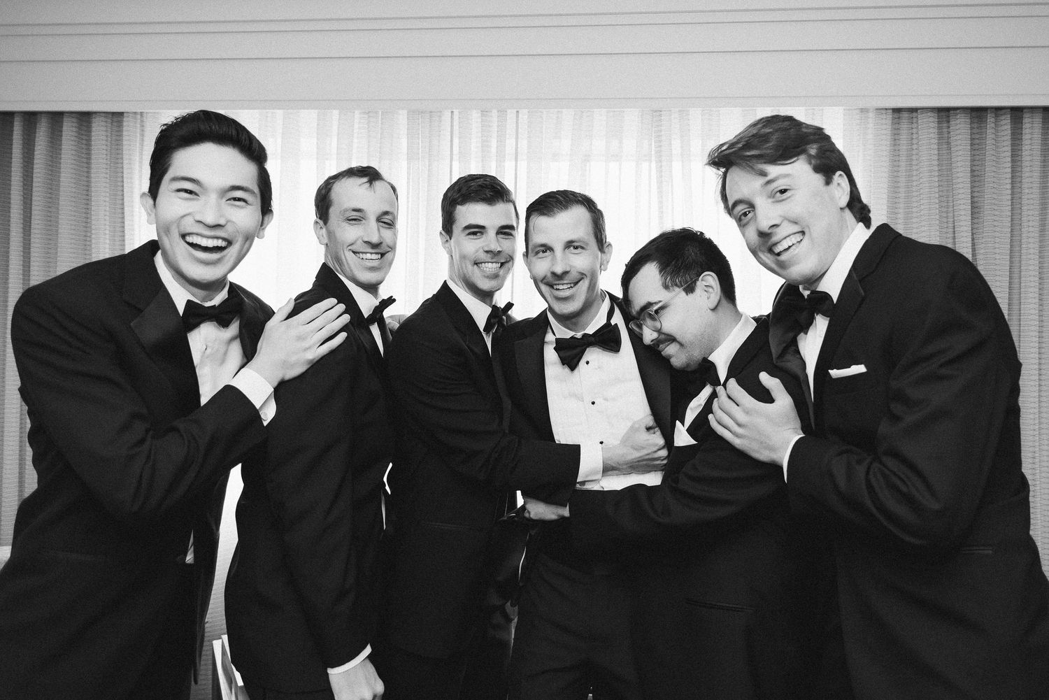 Groom and his groomsmen in a hotel room in Alexandria, Virginia smiling for the camera.