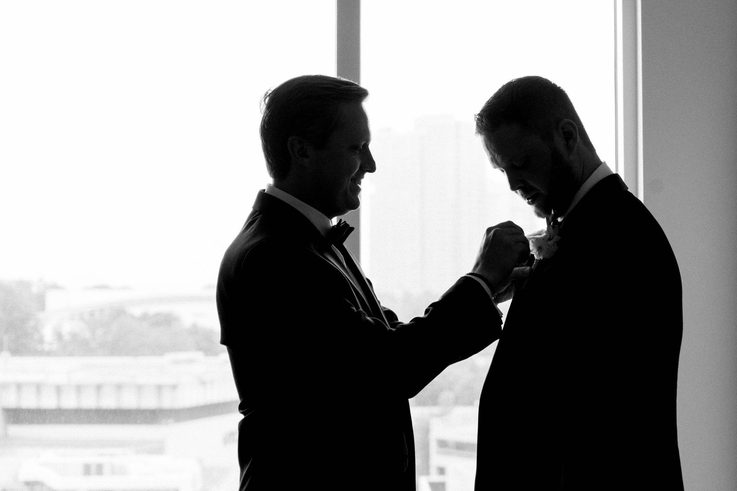 Silhouette photo of groom being helped by his best man.