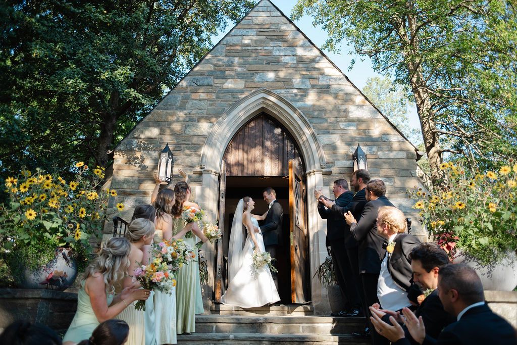 A bride and groom smiling at each other as they exit a stone church in DC wedding.