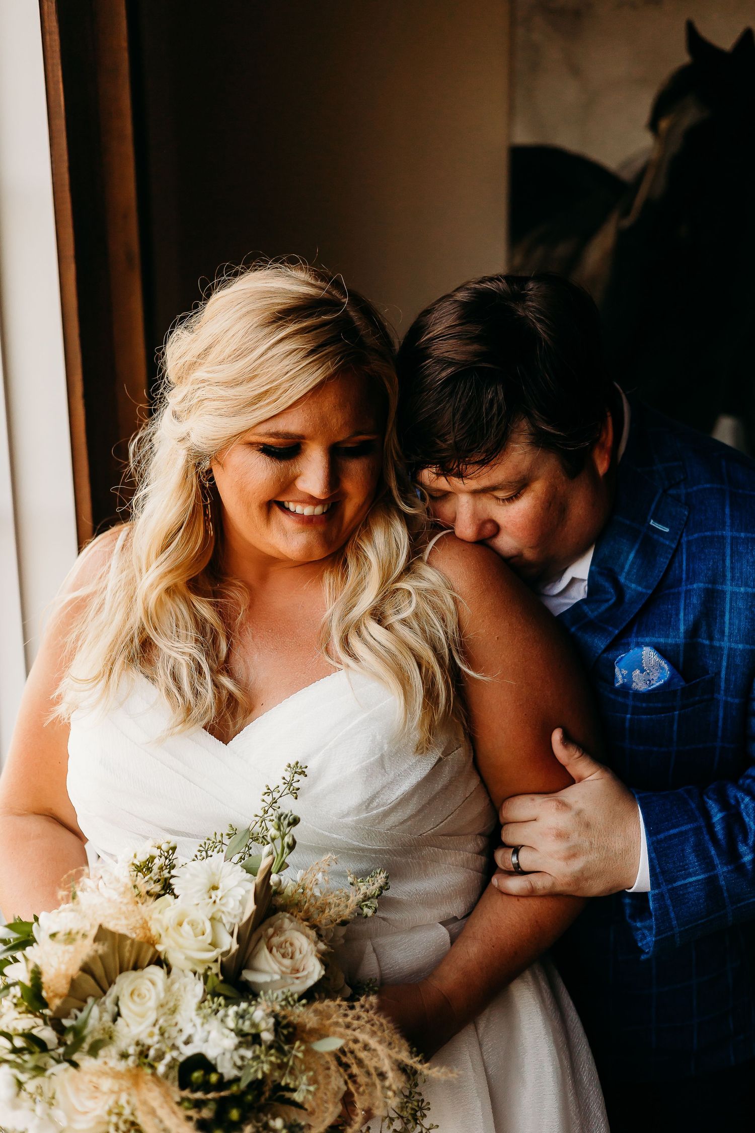 Intimate wedding moment with white bouquet and natural window light.