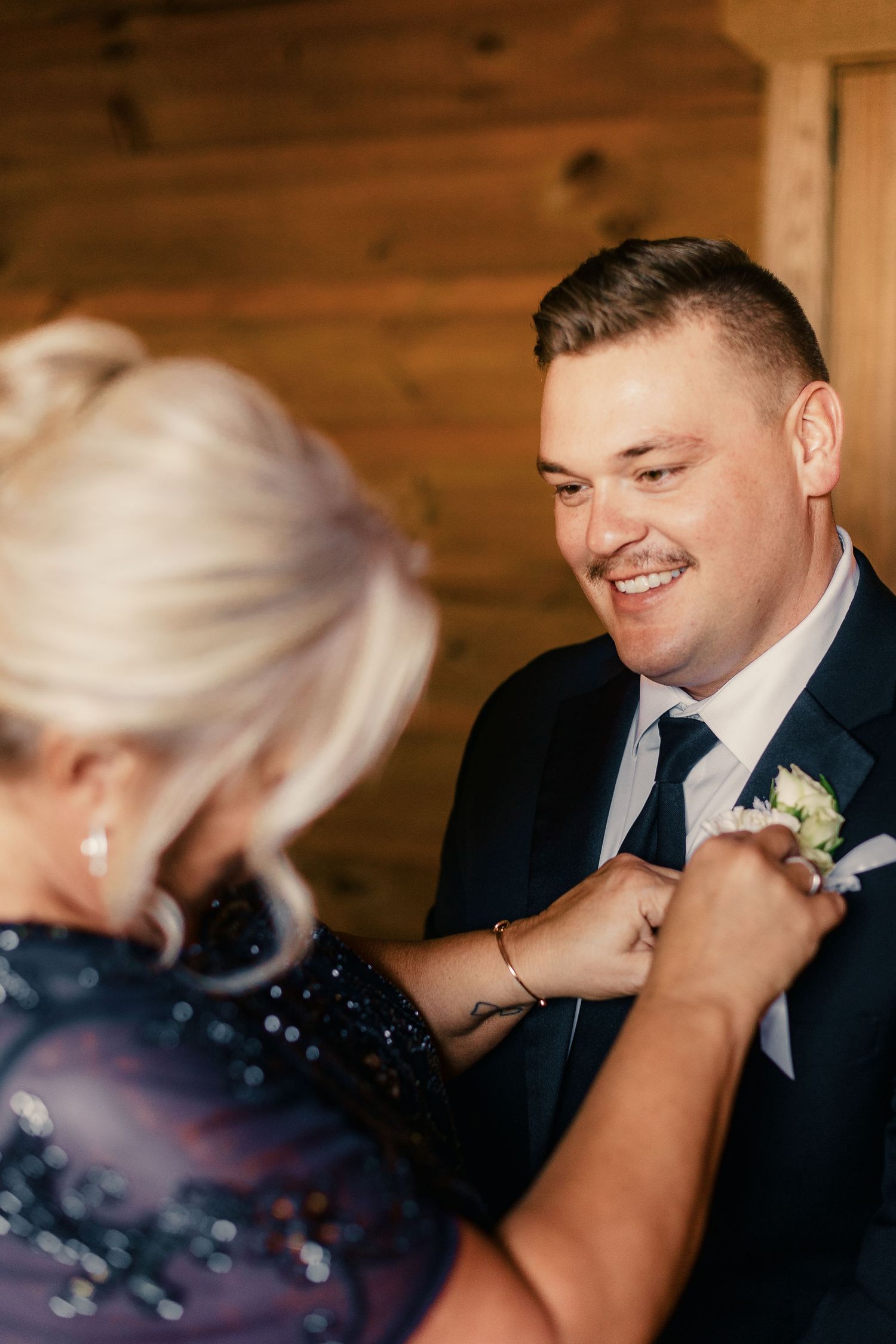 Intimate wedding preparation moment captured in warm wooden interior setting.