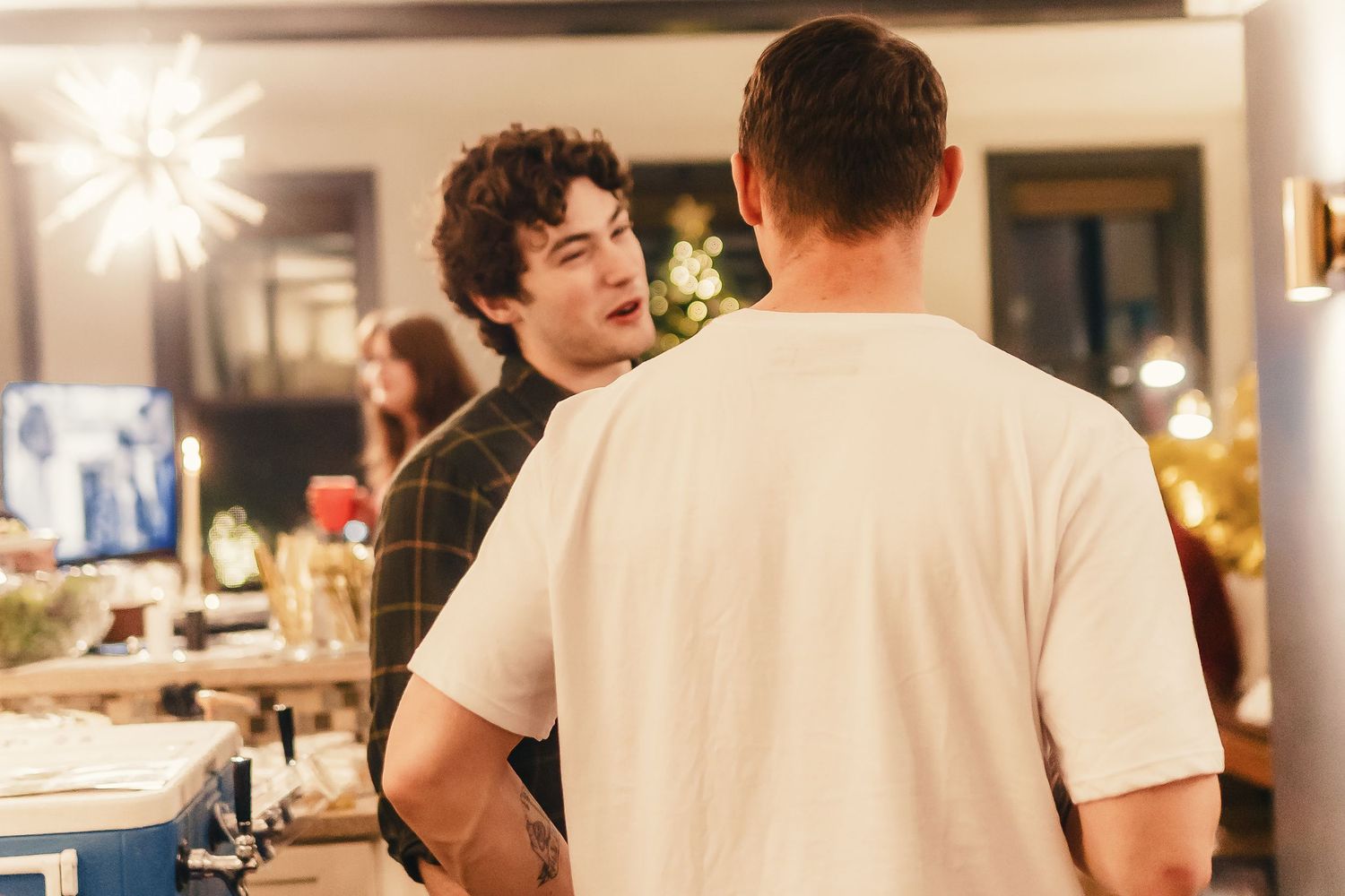 Two people having a conversation in a warmly lit room during what appears to be a social gathering.