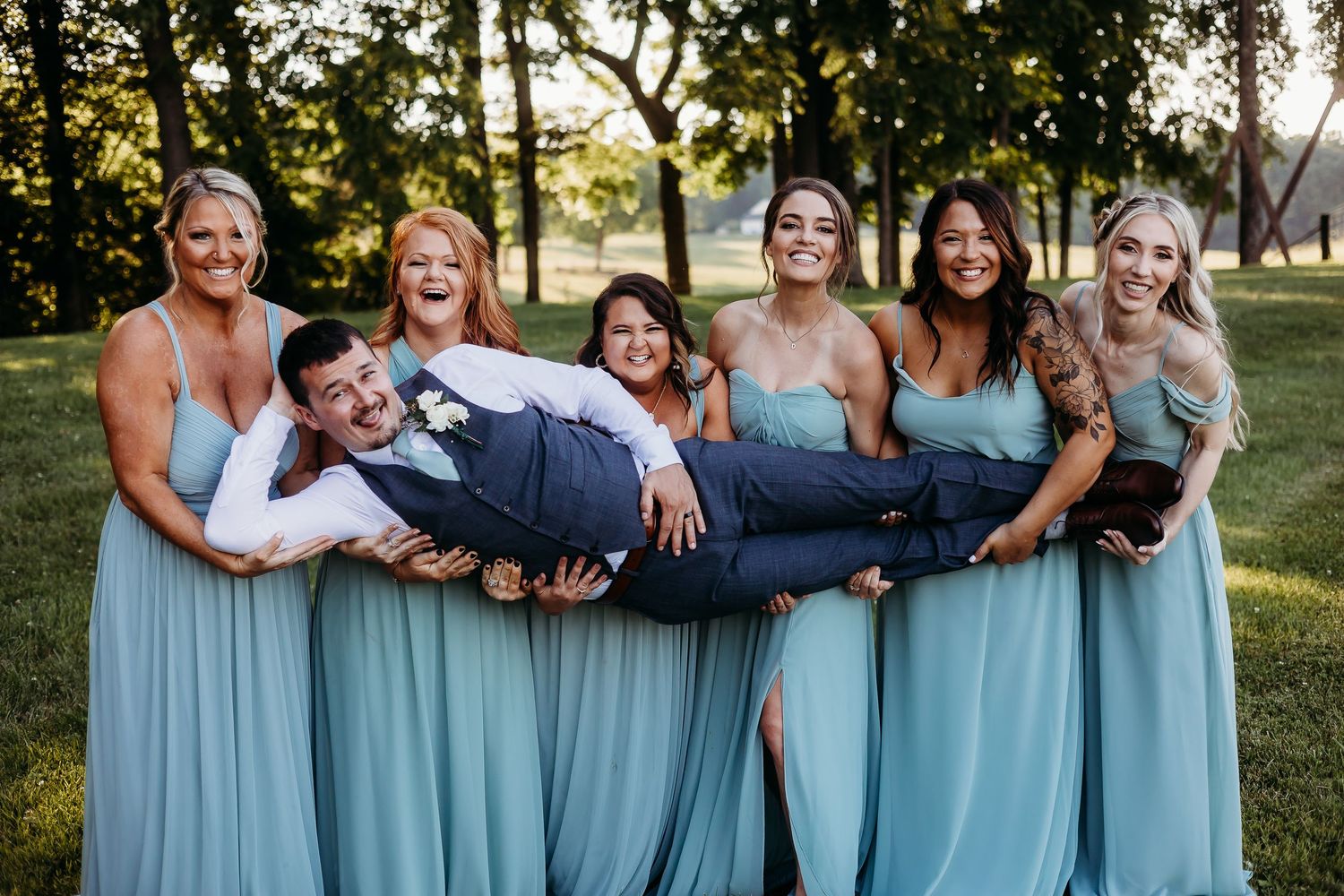 Wedding party in light blue dresses poses together outdoors.