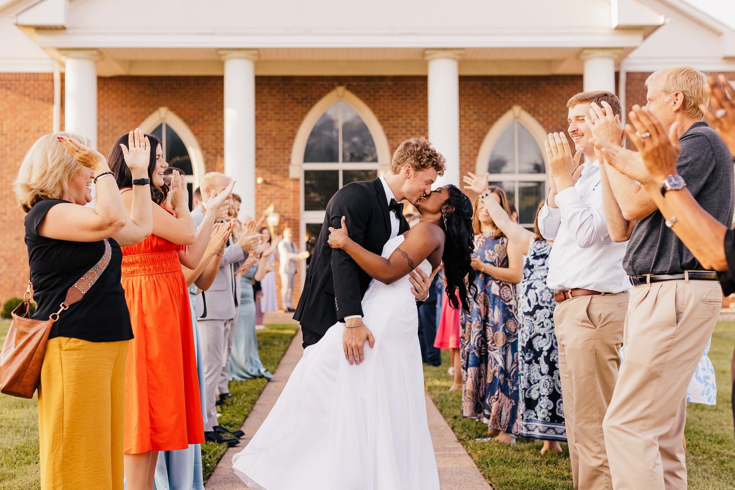 Wedding guests gather outdoors for a celebratory moment at a rustic venue.