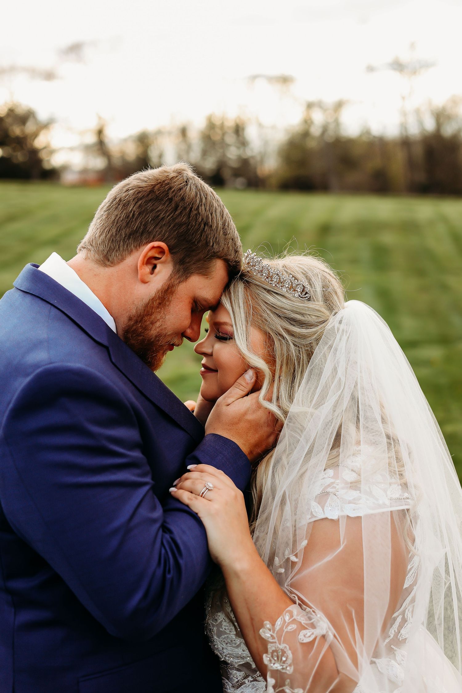 Tender moment between newlyweds sharing a close embrace outdoors.