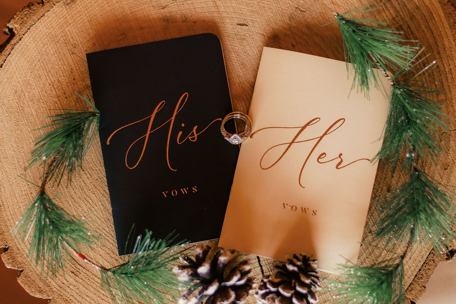 Wedding stationery with pine sprigs and elegant calligraphy on wooden surface.
