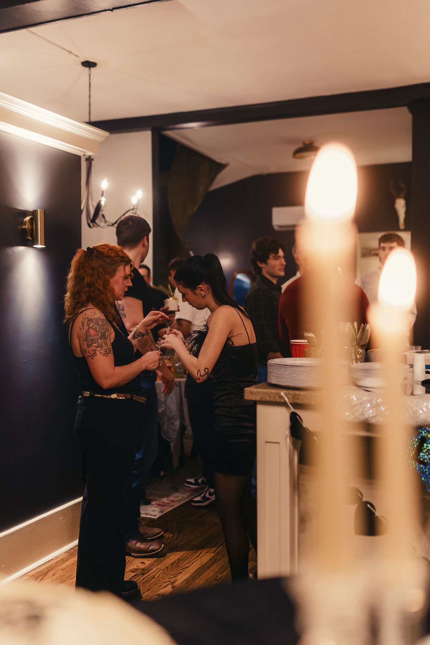 People mingling and socializing in a dimly lit room with modern interior lighting fixtures.