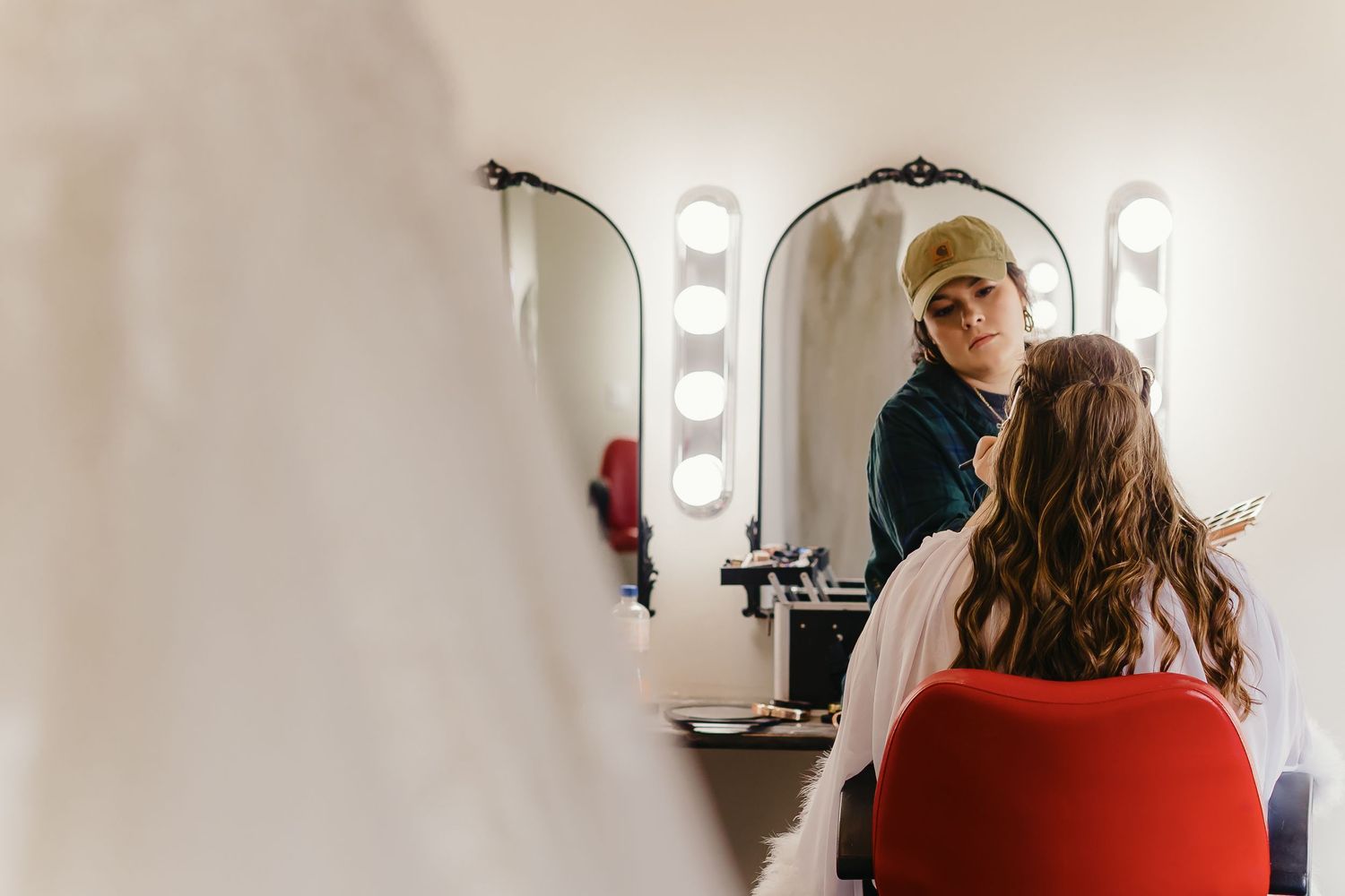 Behind-the-scenes shot of wedding day hair and makeup preparation in dressing room.