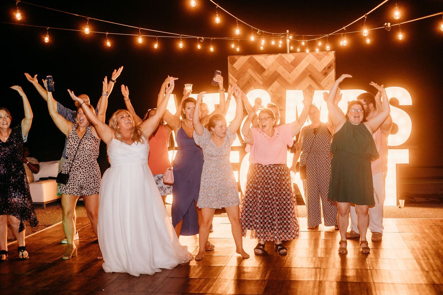 String lights illuminate a nighttime wedding reception dance floor.
