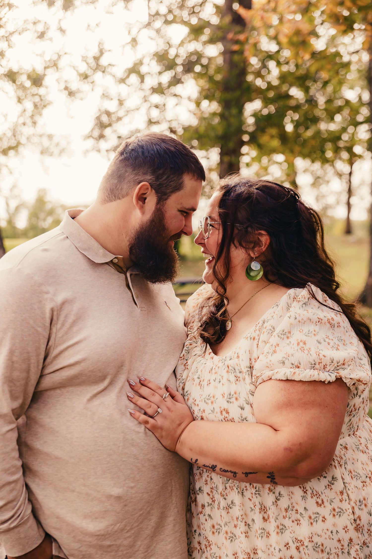 A couple shares an intimate moment outdoors wearing casual attire against a sunlit background.
