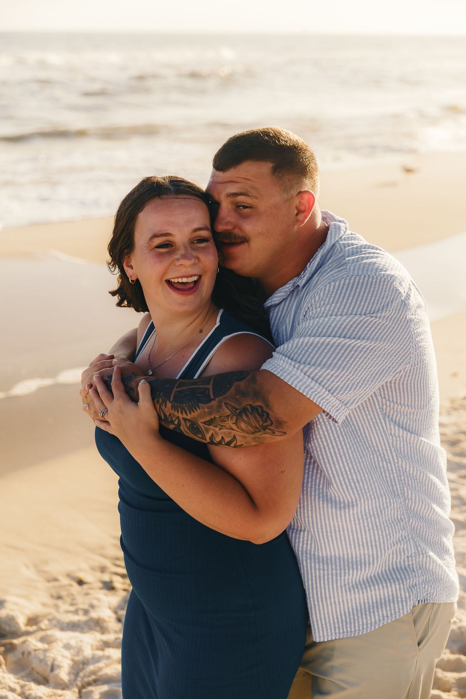 Couple sharing joyful laughter together on beach at golden hour.