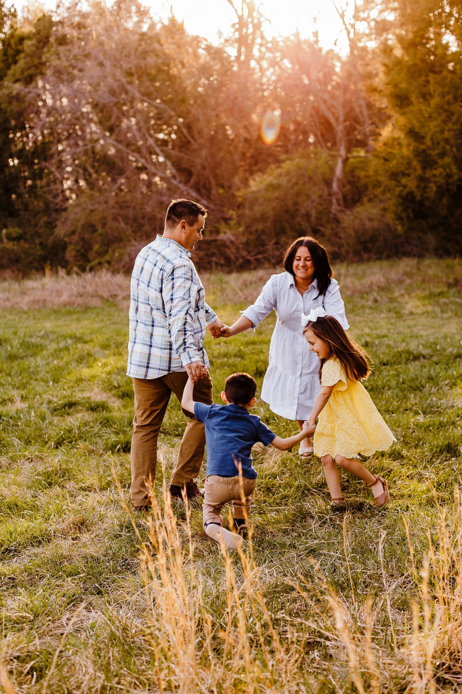 Family walking and playing together in a golden sunset field.