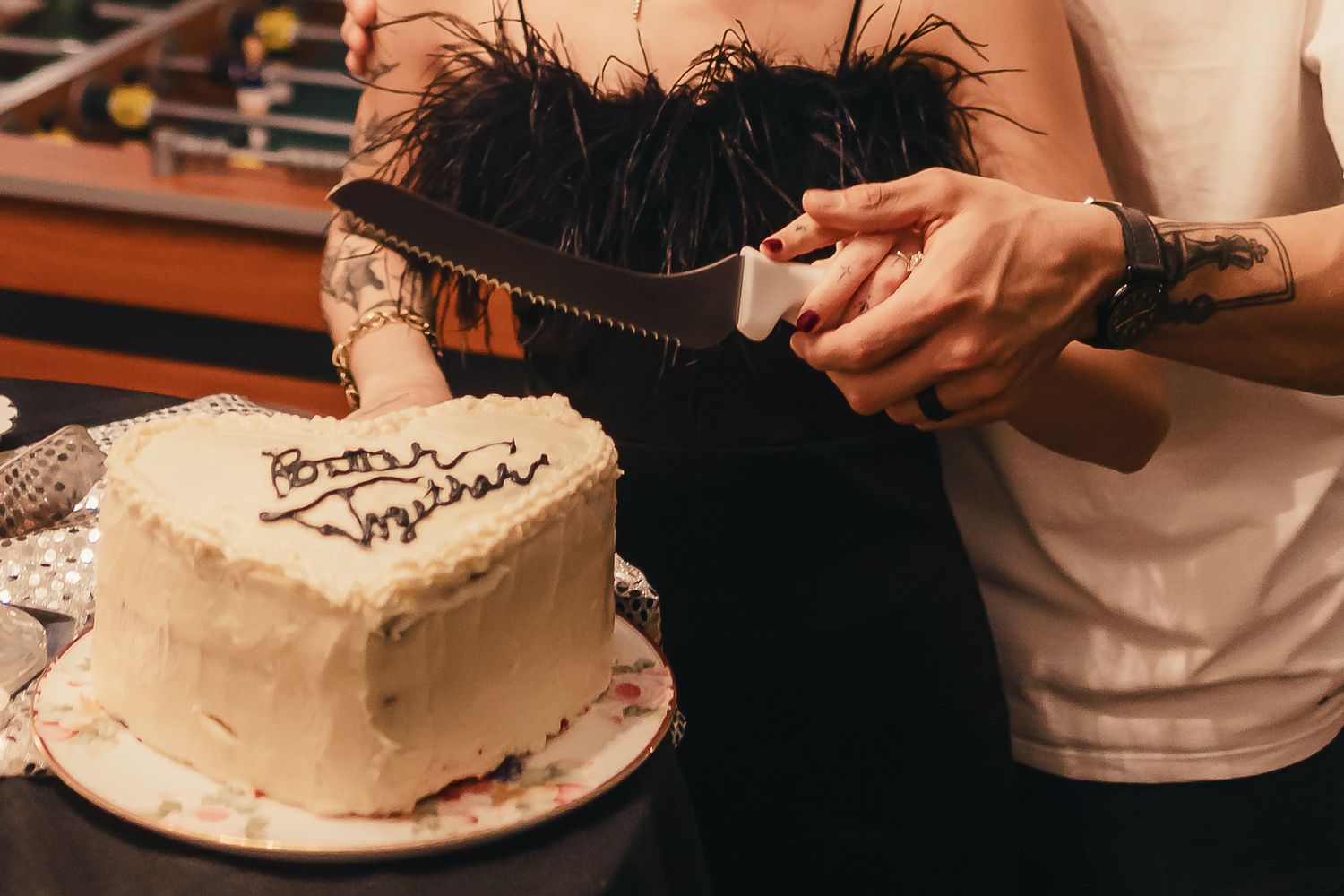A person cuts into a white frosted birthday cake with decorative chocolate drizzle on top.