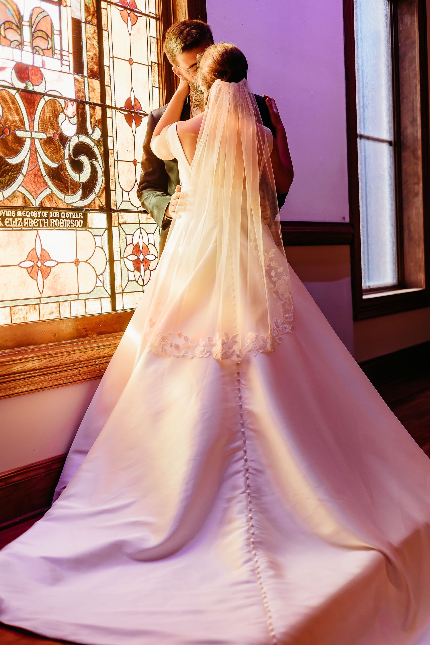 Wedding dress train with intricate button details trailing across church floor.