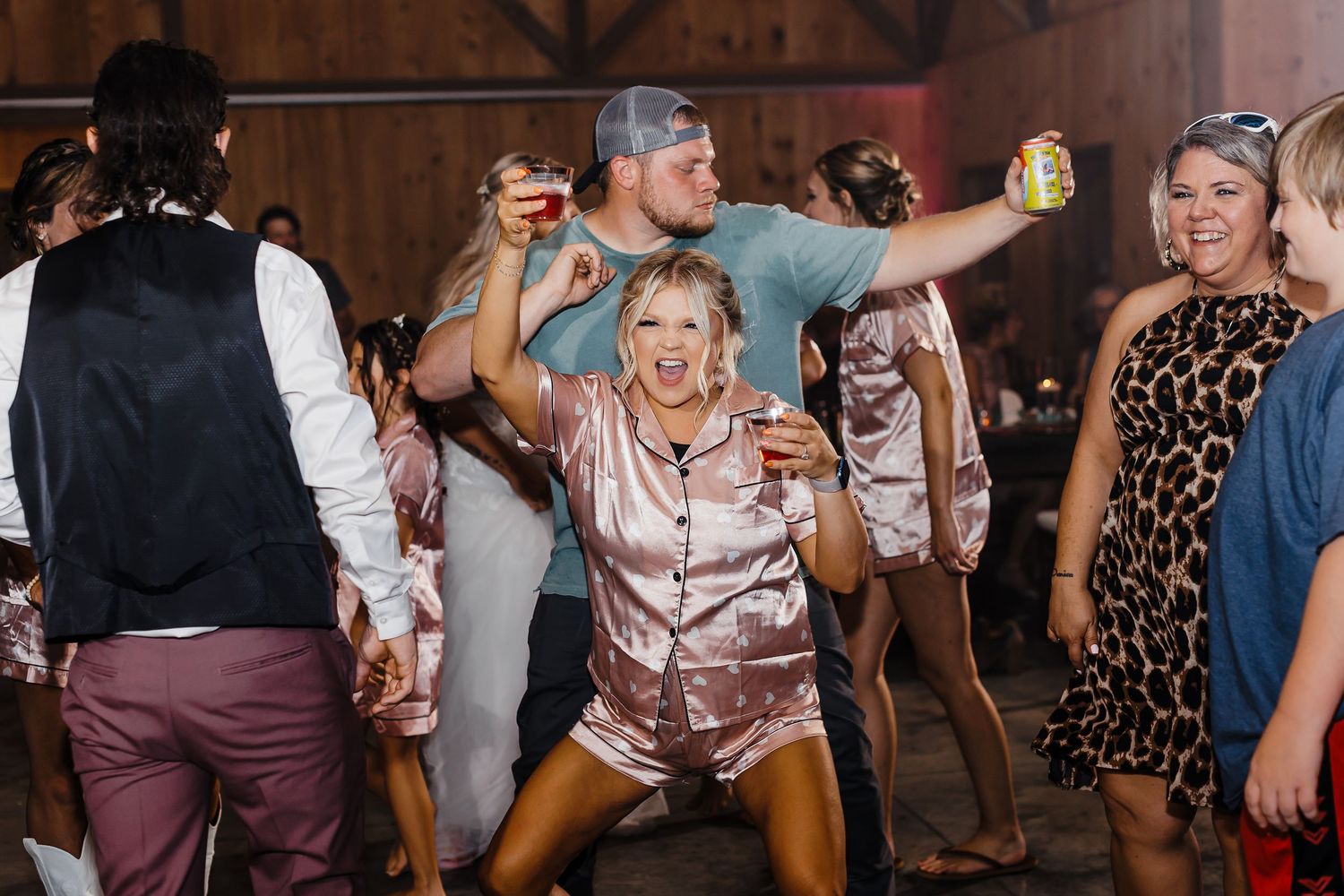 Wedding guests dancing and celebrating at rustic barn reception venue.