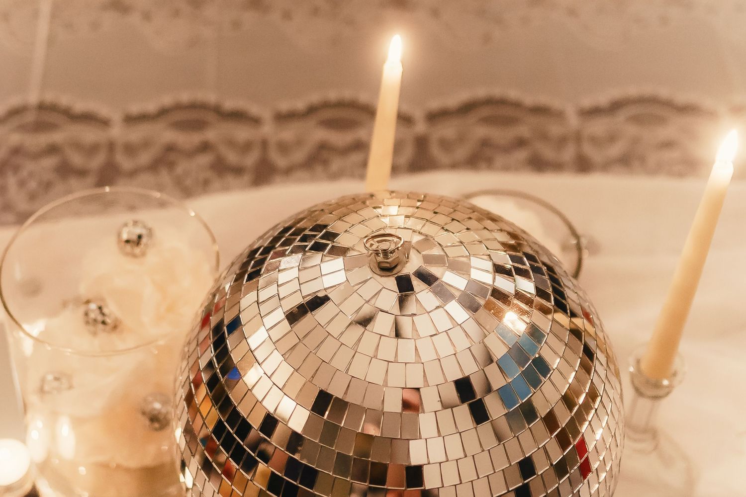 Shiny disco ball ornaments with glowing candles create a festive party atmosphere.