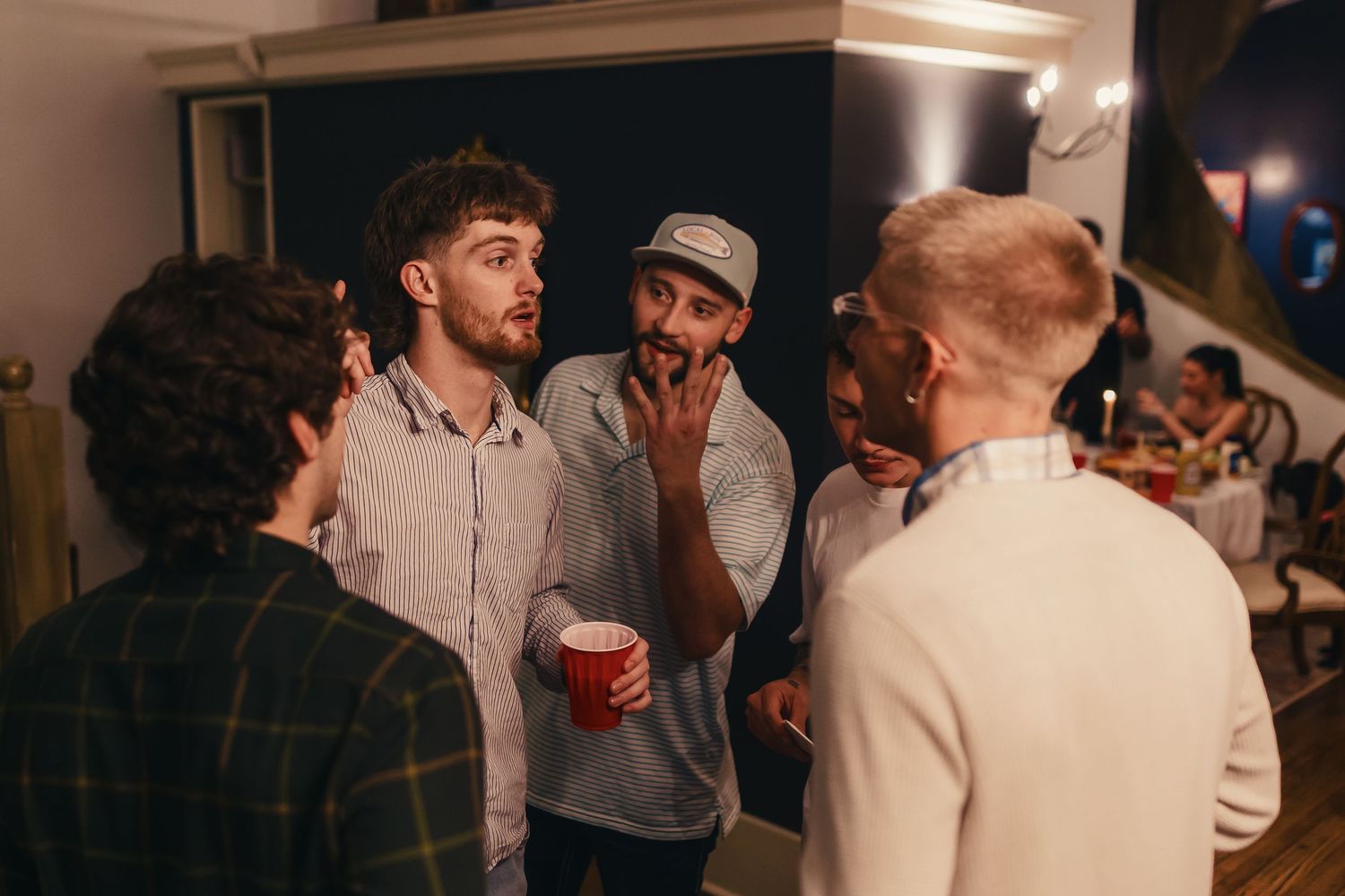 A group of friends having an animated conversation at a casual indoor party.
