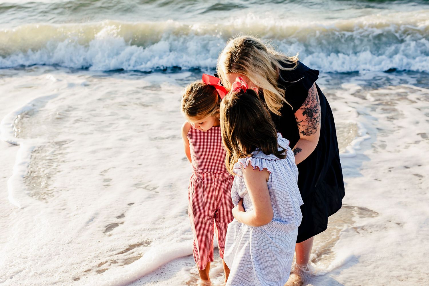Family members walking along beach shoreline with waves crashing.