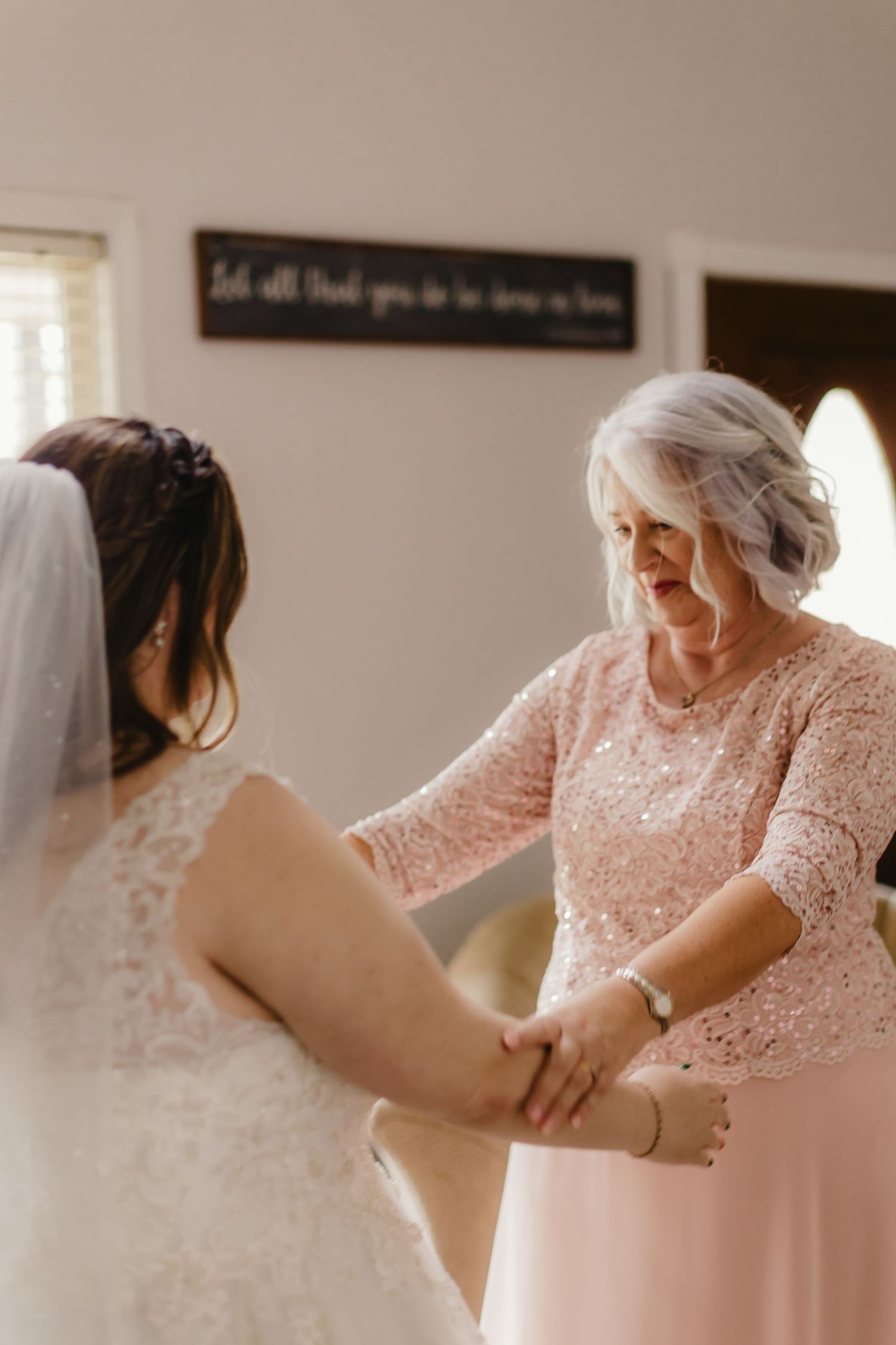 Tender moment between two women in wedding attire sharing an emotional embrace.