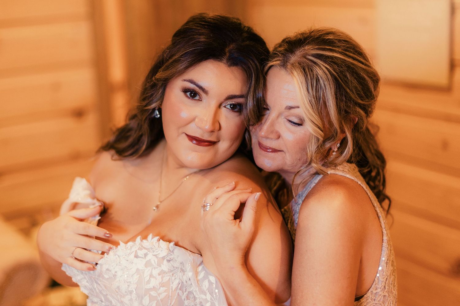 Warm-toned wedding photography captures emotional moment between wedding attendees.