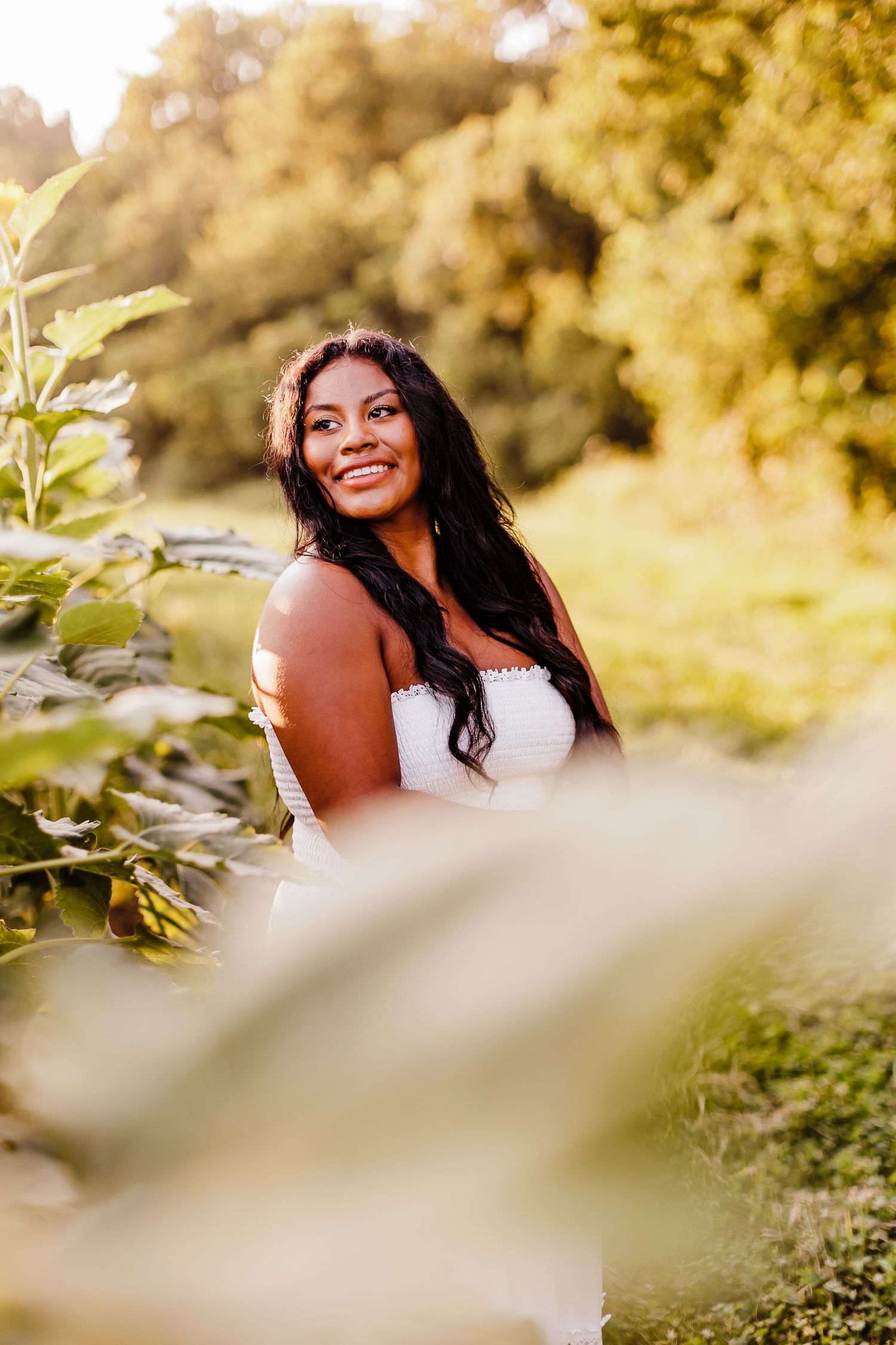 Portrait in golden sunlight with soft focus foreground elements.