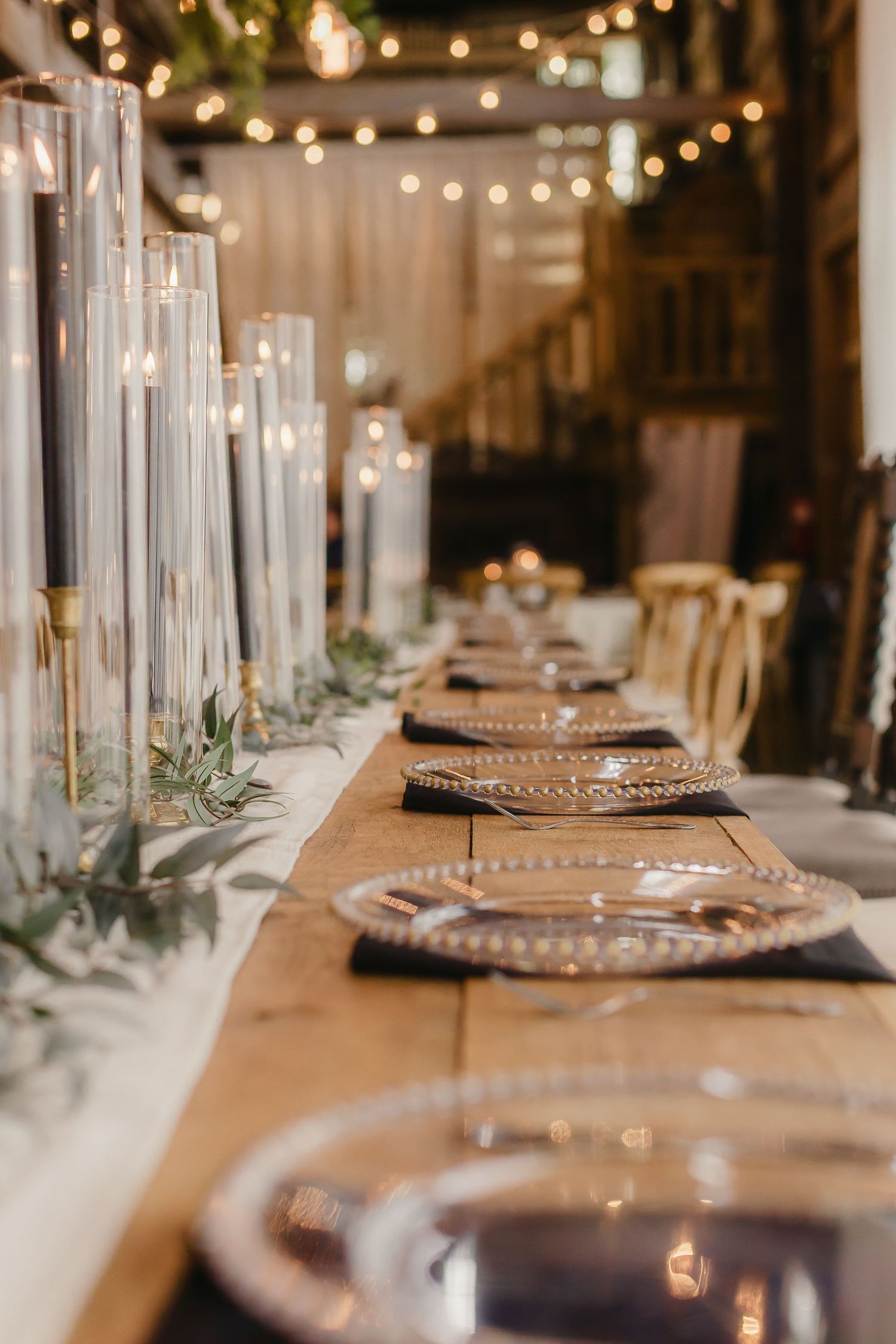 Elegant table setting with beaded charger plates and string lights overhead creating a romantic dining atmosphere.