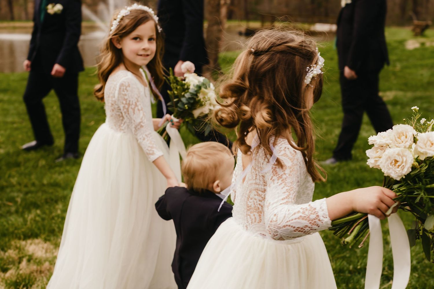 Wedding party celebrates outdoors on a grassy lawn with elegant floral arrangements.