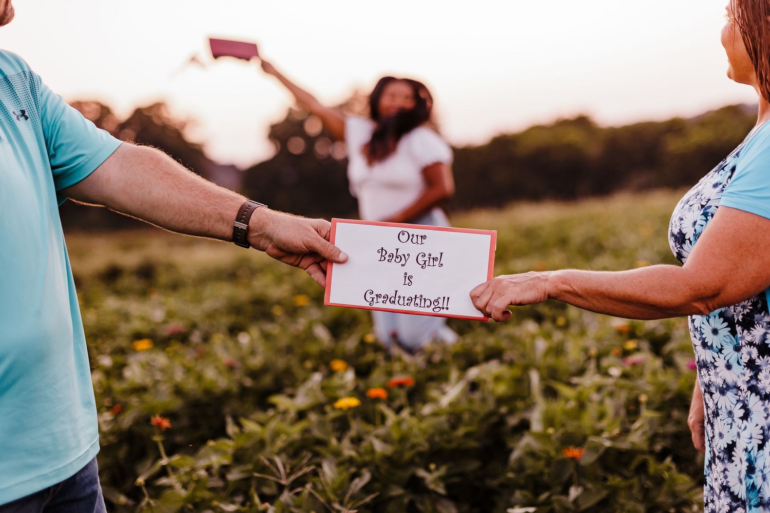 Hands exchanging small cards or notes in an outdoor setting at sunset.