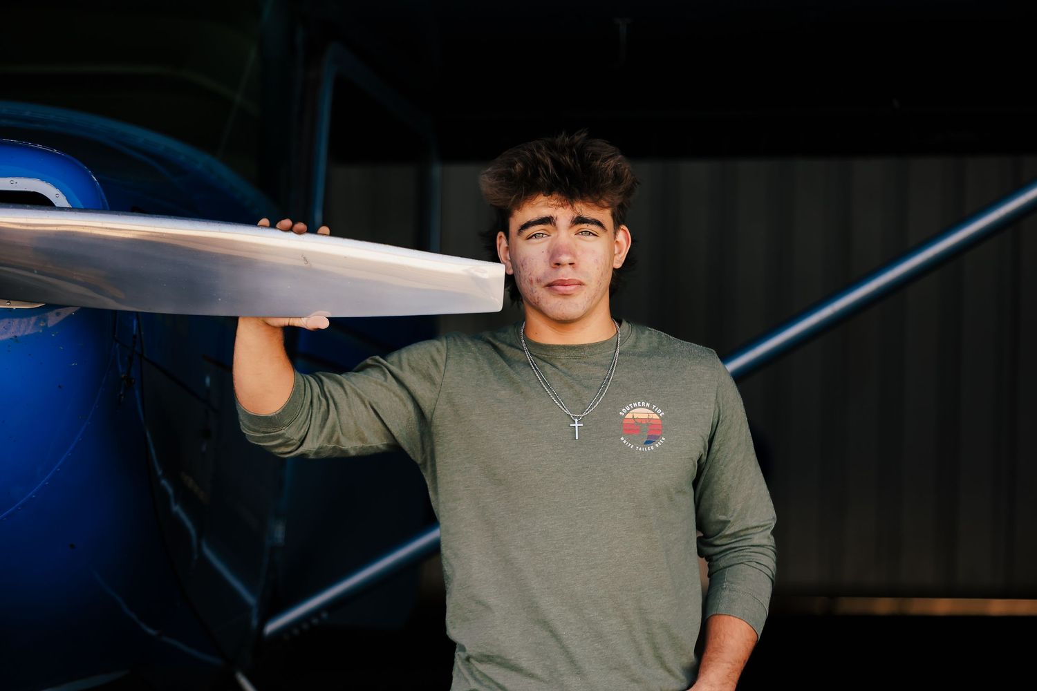Person in green sweater standing next to a small aircraft at dusk.