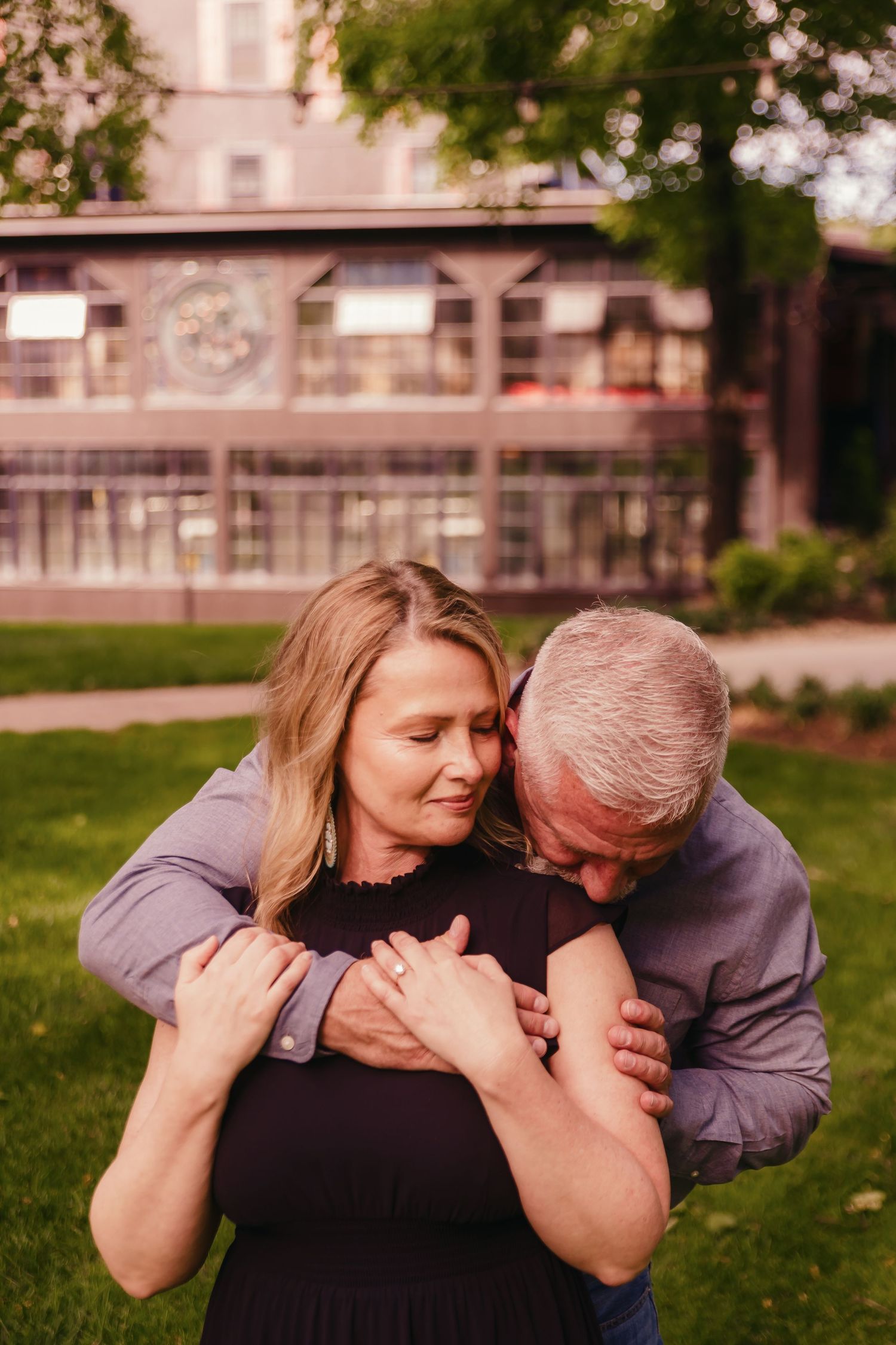 Candid laughing moment shared between two people on grassy lawn.